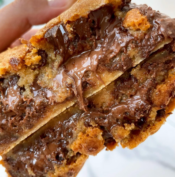 Close-up of a chocolate chip cookie with a gooey chocolate filling.