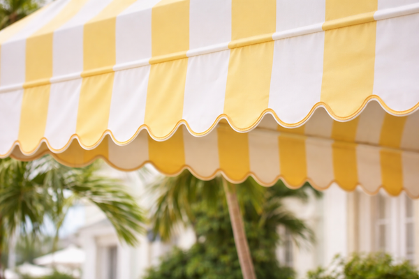 Yellow and white striped awning with blurred greenery and building in the background
